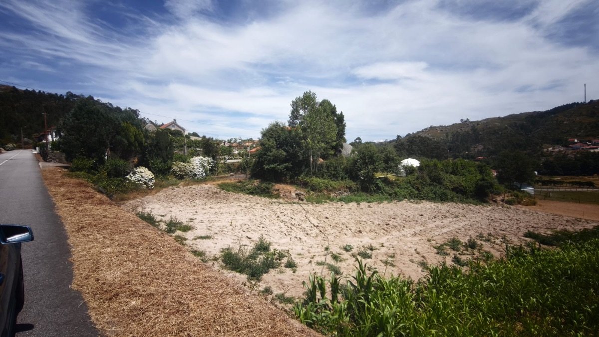 The village land seen from the road, with ploughed ground and neighbouring houses